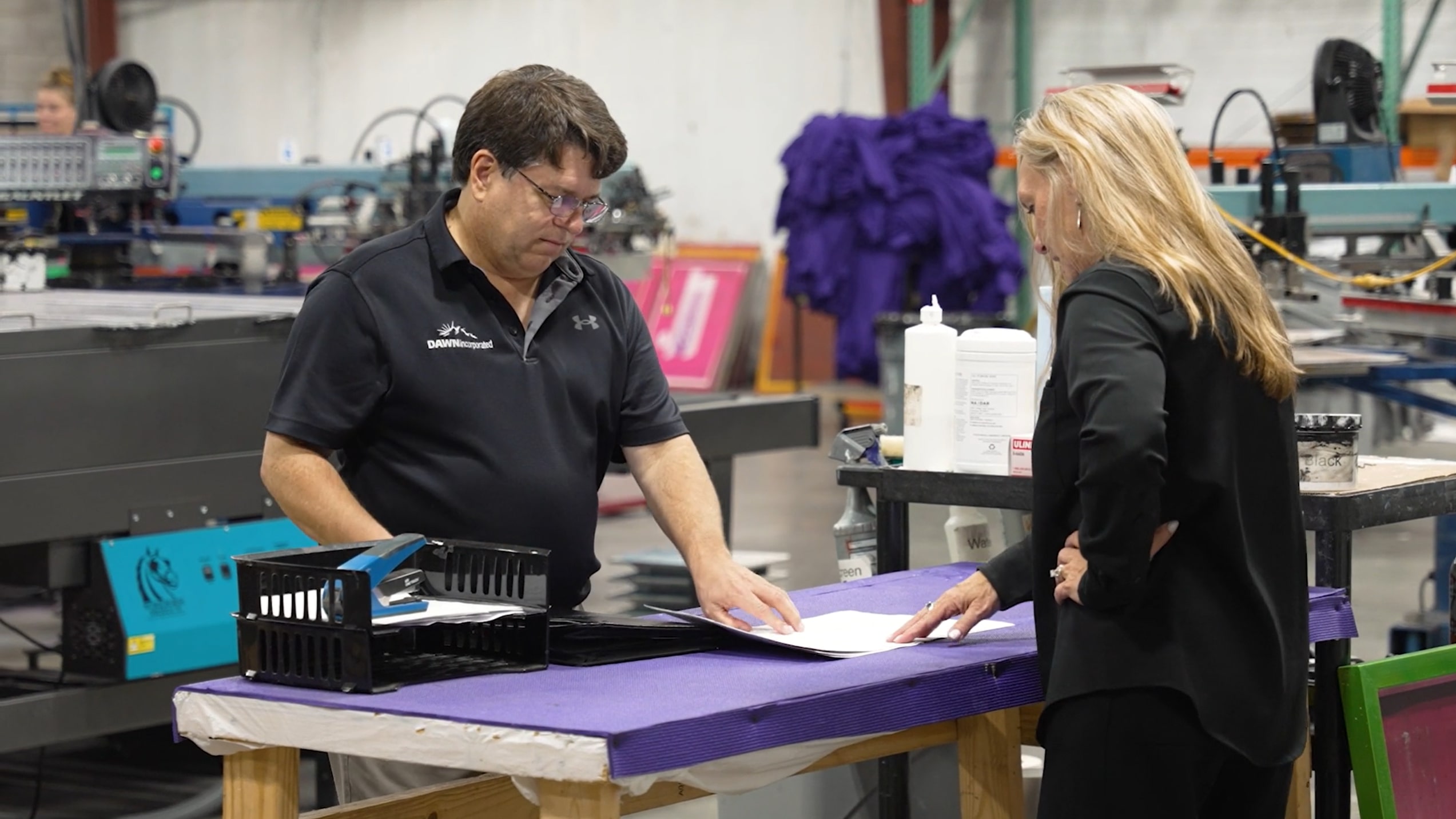 Man and woman looking over contract in factory